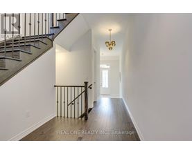A hallway with a staircase and a chandelier.