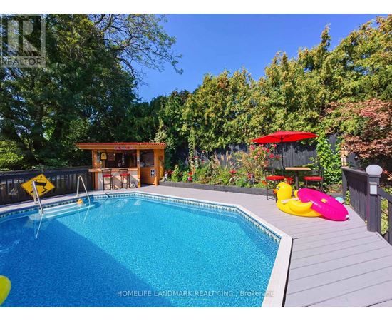 A pool surrounded by trees and a deck with a hot tub.