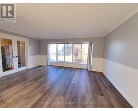 A spacious room with wooden flooring and a large window.