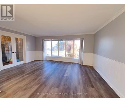 A spacious room with wooden flooring and a large window.