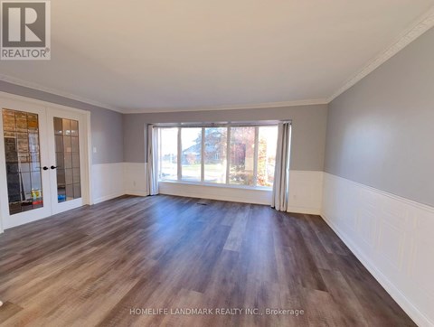 A spacious room with wooden flooring and a large window.