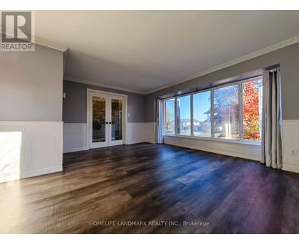 A spacious room with wooden floors and large windows.