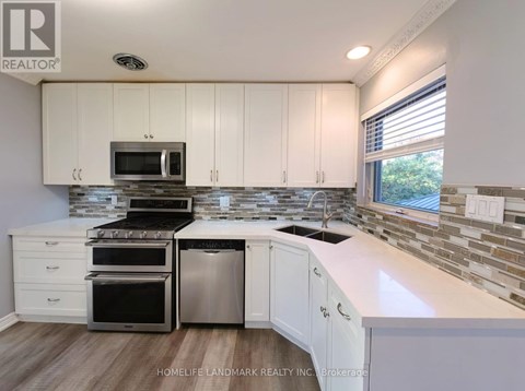 A kitchen with white cabinets and a stone backsplash.