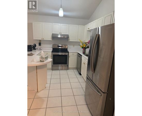 A kitchen with white cabinets and a stainless steel refrigerator.
