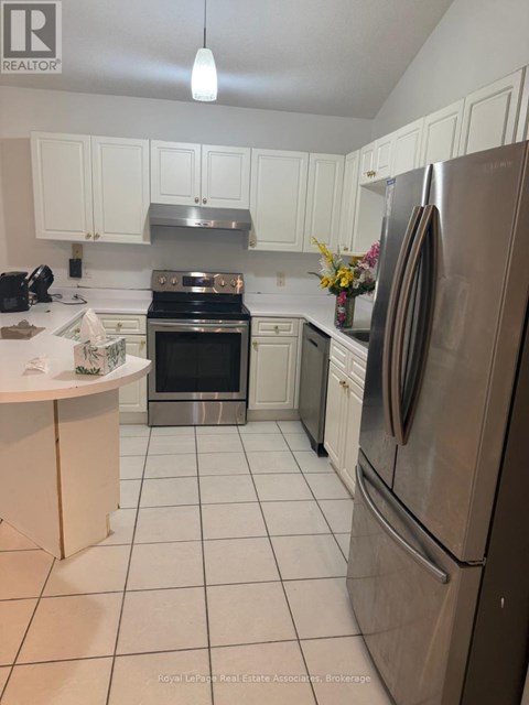 A kitchen with white cabinets and a stainless steel refrigerator.