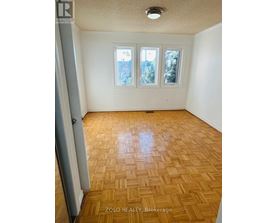 A room with wooden flooring and a window showing a view of trees.