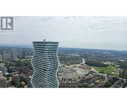 A tall building with a glass facade stands out against a cloudy sky.