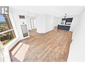 A large open room with wooden flooring and white walls.