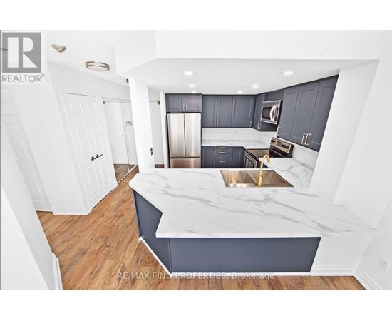A modern kitchen with a marble countertop and stainless steel appliances.