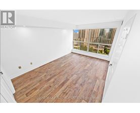 A room with wooden flooring and a window overlooking a cityscape.