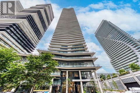 A tall building with a unique triangular top is surrounded by other buildings.
