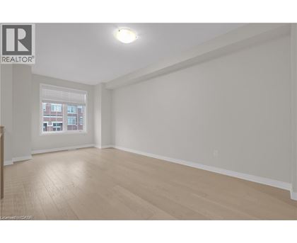 A spacious room with wooden flooring and a window.