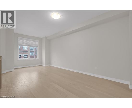 A spacious room with wooden flooring and a window.