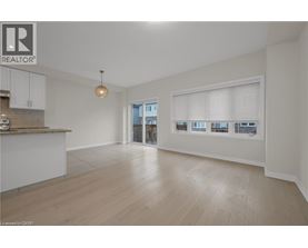 A spacious living room with a kitchen area and a view of the outside through the window.
