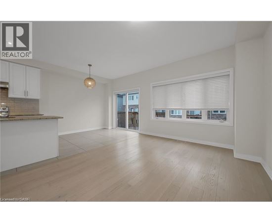 A spacious living room with a kitchen area and a view of the outside through the window.