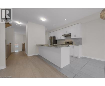 A modern kitchen with white cabinets and a wooden floor.
