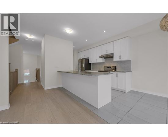 A modern kitchen with white cabinets and a wooden floor.