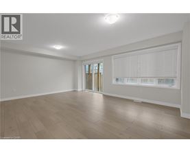 A spacious room with wooden flooring and a sliding glass door.