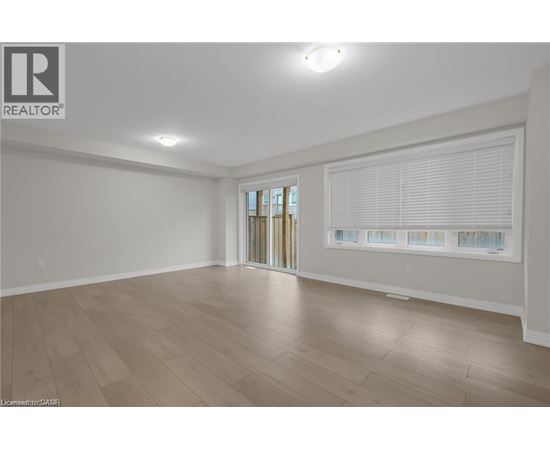 A spacious room with wooden flooring and a sliding glass door.