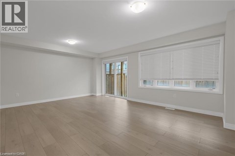 A spacious room with wooden flooring and a sliding glass door.