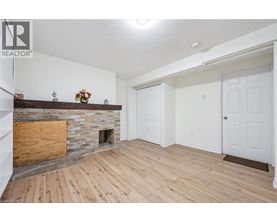 A living room with a stone fireplace and wooden floors.