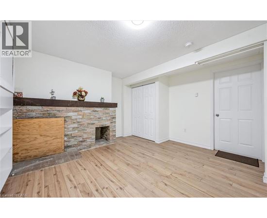A living room with a stone fireplace and wooden floors.