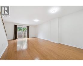 A spacious room with wooden flooring and white walls.