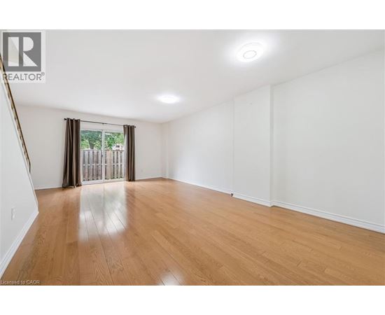 A spacious room with wooden flooring and white walls.