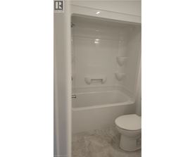A white toilet sits next to a bathtub in a bathroom.