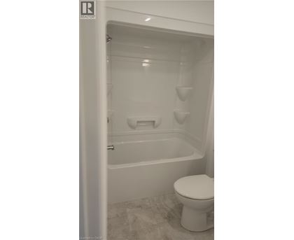 A white toilet sits next to a bathtub in a bathroom.