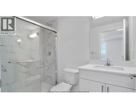 A white bathroom with a marble shower and toilet.