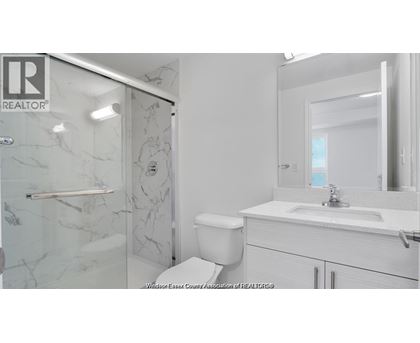 A white bathroom with a marble shower and toilet.