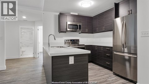 A modern kitchen with dark wood cabinets and stainless steel appliances.