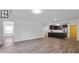 A spacious living room with a kitchenette in the background.