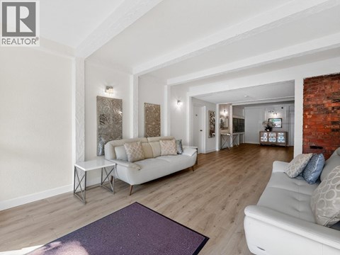 A living room with a white couch and a purple rug.