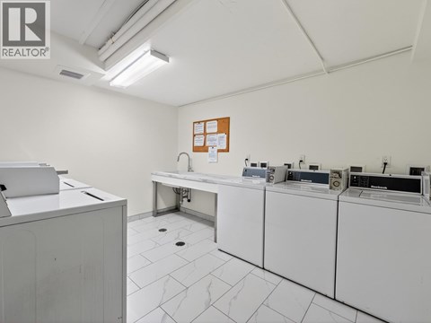 A clean, white-walled room with a row of white appliances and a white cabinet.