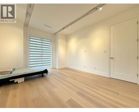A bedroom with a bed, wooden floors, and white walls.