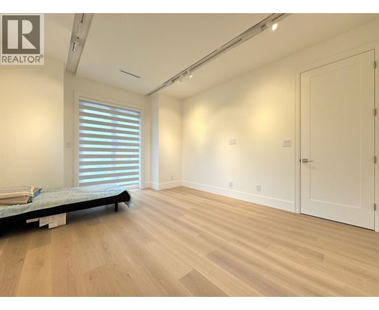 A bedroom with a bed, wooden floors, and white walls.