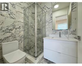 A bathroom with a marble wall and a white toilet.
