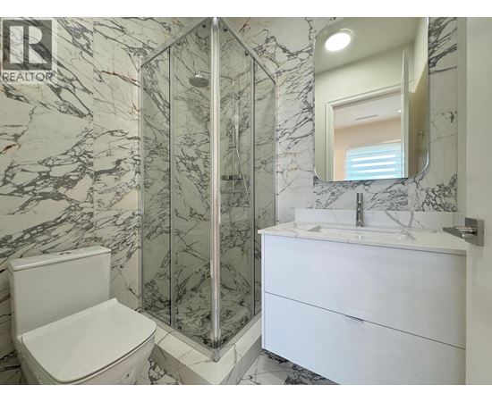 A bathroom with a marble wall and a white toilet.