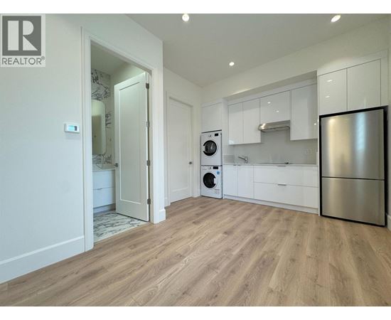 A modern kitchen with a refrigerator, oven, and washing machine.