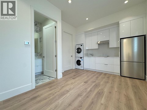 A modern kitchen with a refrigerator, oven, and washing machine.