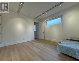 A bedroom with a bed, wooden floors, and a window.