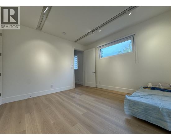 A bedroom with a bed, wooden floors, and a window.