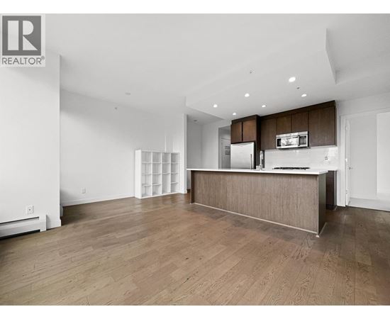 A spacious, empty room with wooden floors and white walls.