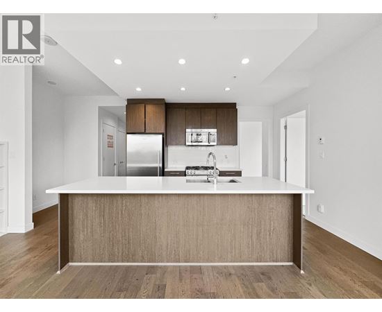 A modern kitchen with a large island and wooden cabinets.