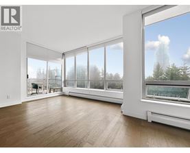 A large, empty room with a view of trees outside the windows.