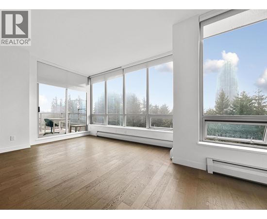 A large, empty room with a view of trees outside the windows.