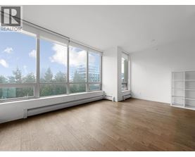 A large, empty room with wooden floors and large windows.