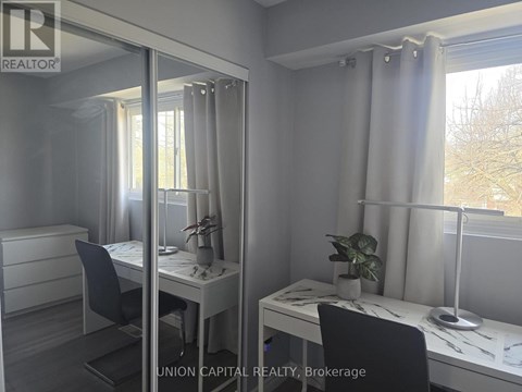 A room with a desk, chair, and mirror.